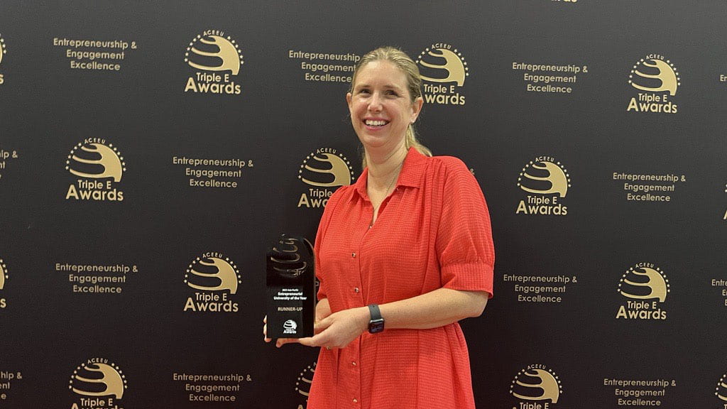Image of Darsel Keane wearing a red dress and holding an award.